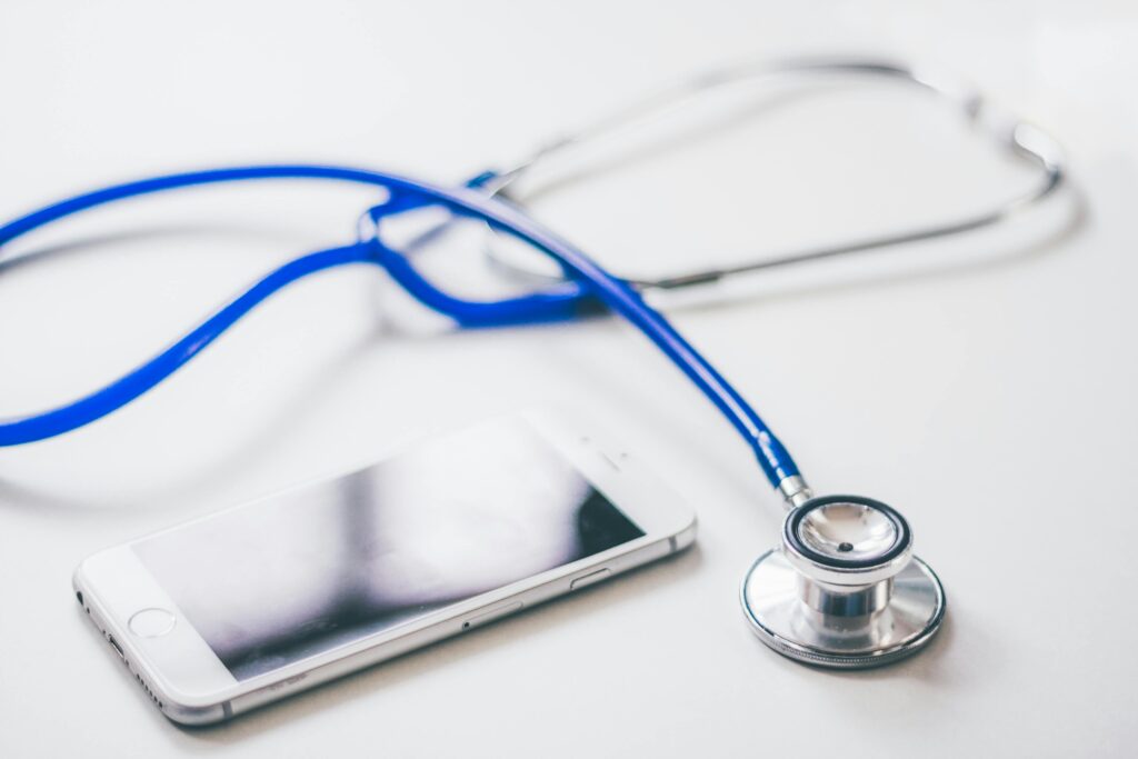 pexels-photo-48603-48603 A smartphone and blue stethoscope on a clean white surface, emphasizing modern healthcare.