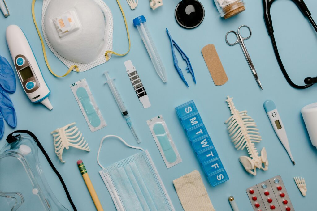 pexels-photo-7722927-7722927-1 A comprehensive flat lay of diverse medical supplies including PPE and diagnostic equipment on a blue surface.